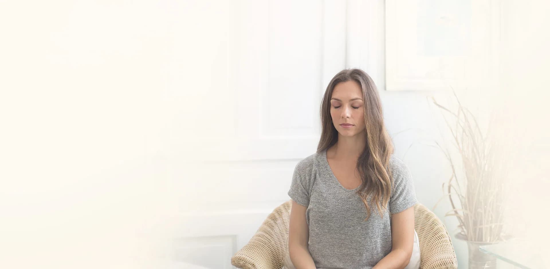 A woman meditating in a bright, quiet room