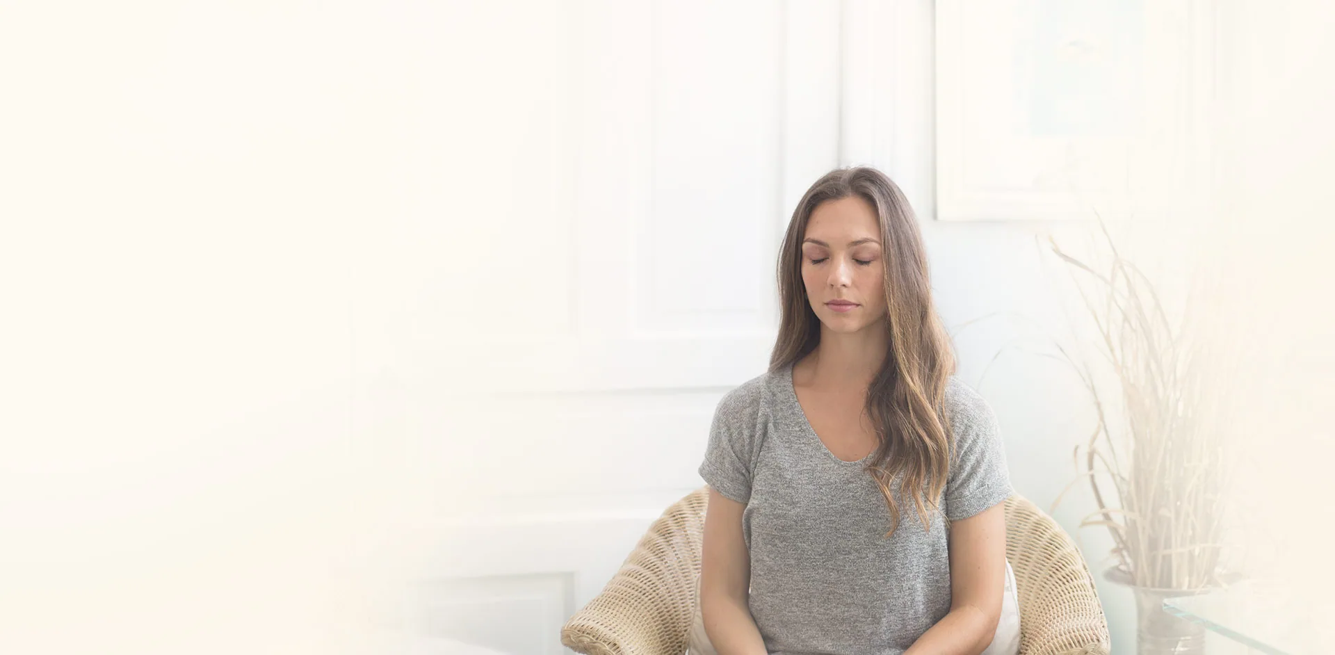A woman meditating in a bright, quiet room